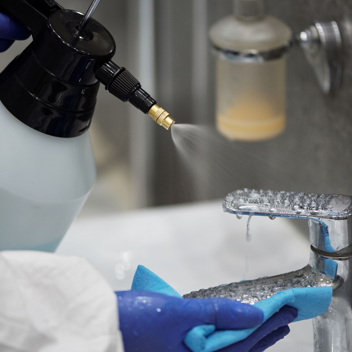 Professional cleaner disinfecting and wiping a bathroom faucet during deep cleaning services in Kaysville, UT