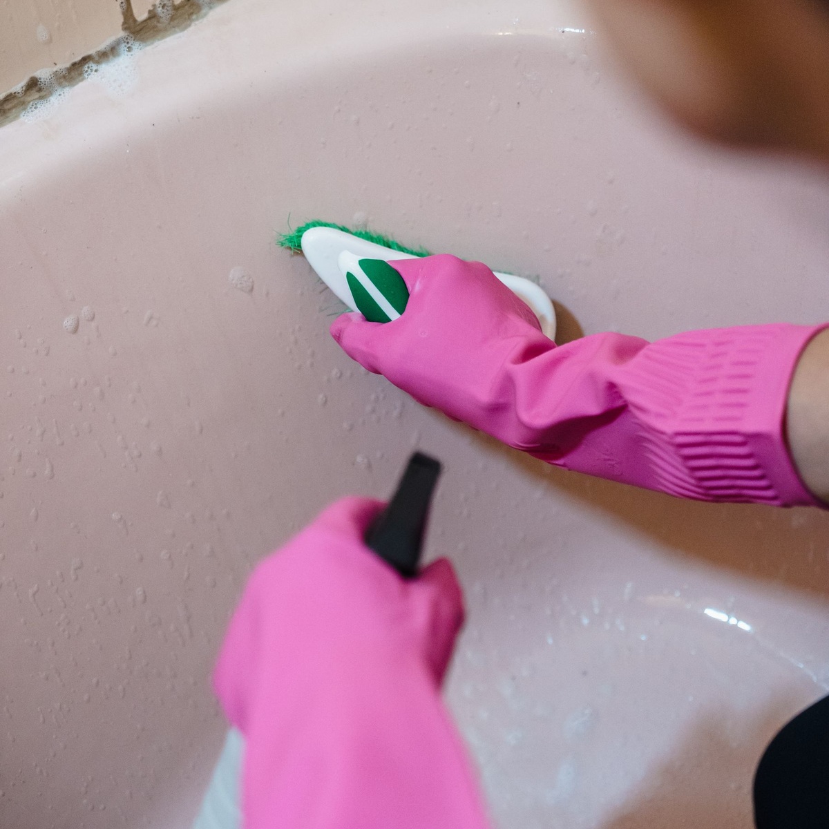 Professional cleaner scrubbing a bathtub surface during deep cleaning services near me
