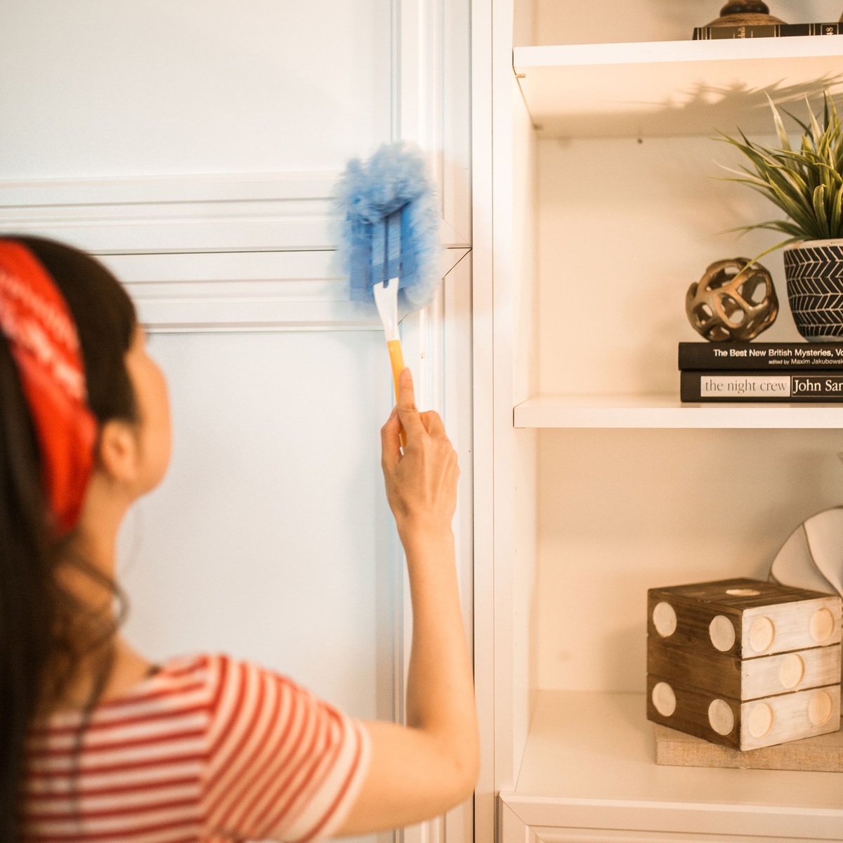 Professional cleaner dusting shelving and trim during deep cleaning services in Saratoga Springs, UT
